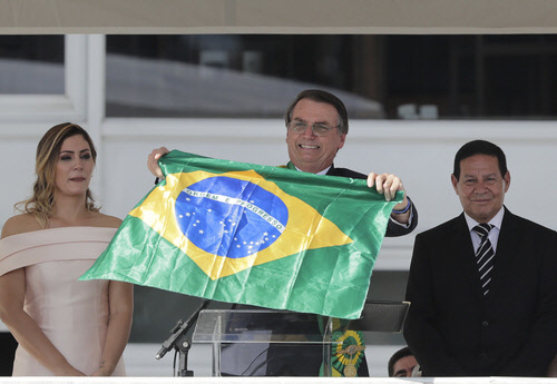 1일(현지시간) 브라질 수도 브라질리아 대통령궁에서 자이르 보우소나루 대통령이 국기를 들고 환하게 웃고 있다. <AP 연합뉴스>